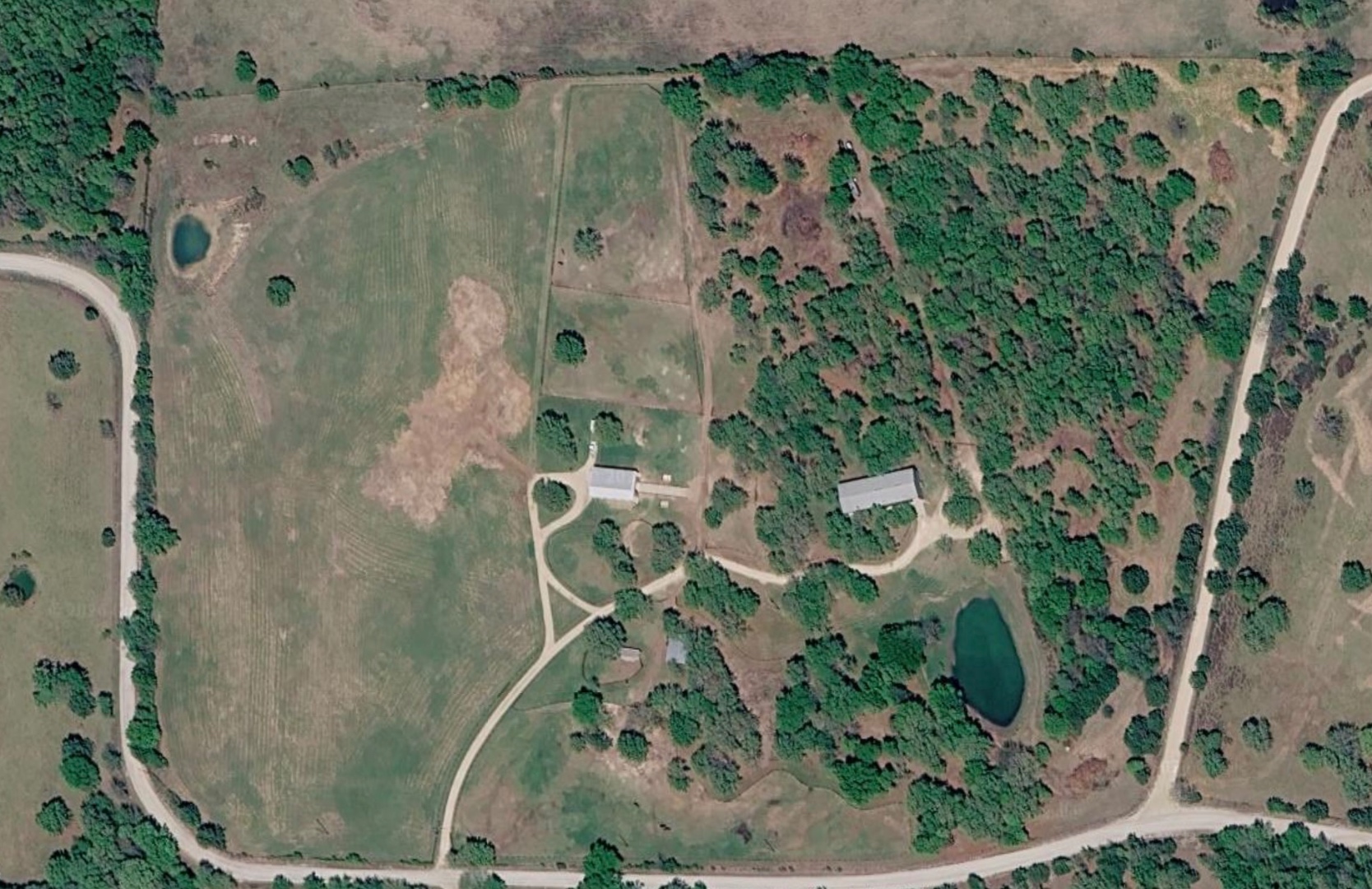 Aerial view of Bent Tree Ridge — nearly 40 acres of pasture and woods with two ponds, the barn, and driveways winding through the property.