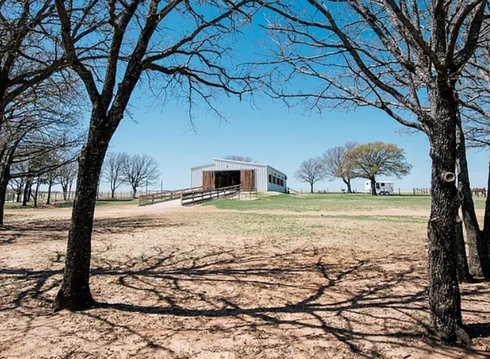 The Bent Tree Ridge barn framed by oak trees.