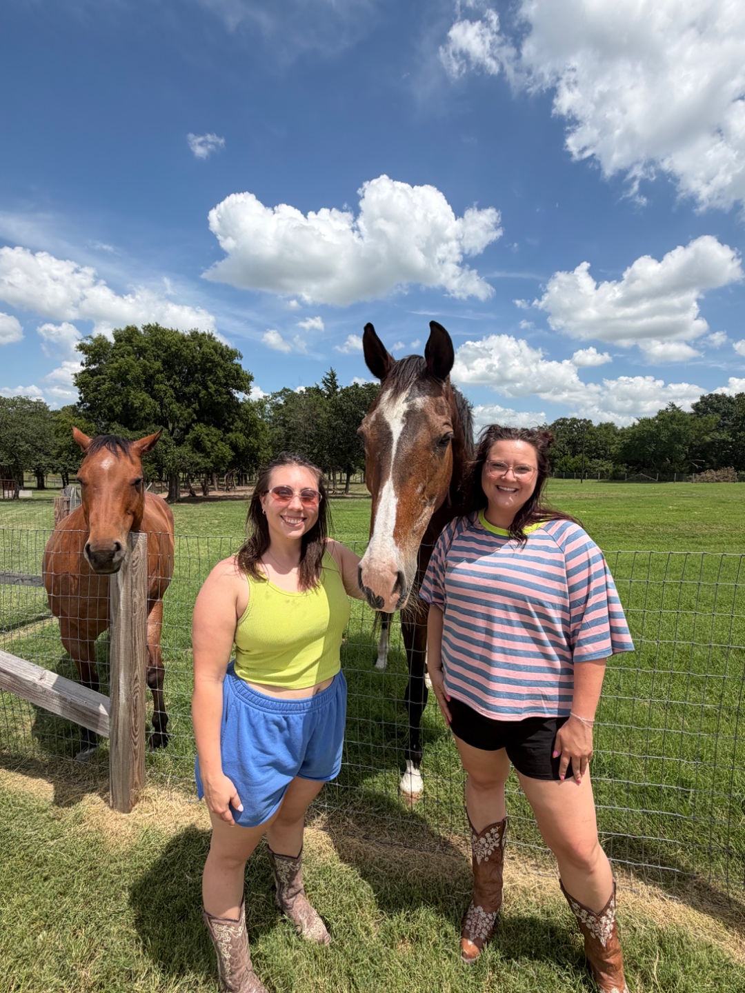 Two guests smiling with two horses along the fence line at Bent Tree Ridge.